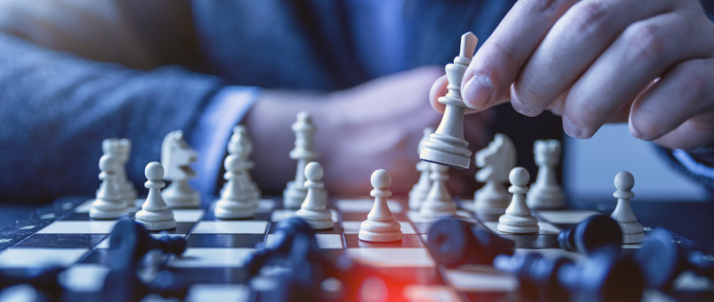 Een persoon in pak, gericht op digitalisering, beweegt een wit schaakstuk op een schaakbord, wat strategisch risicomanagement belichaamt.