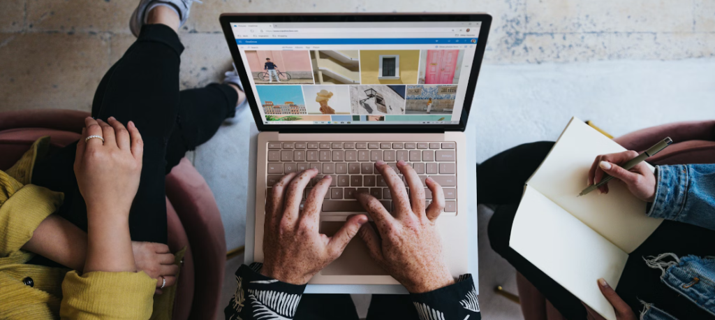 Op een computermonitor wordt een afbeelding weergegeven van een persoon die een verrekijker vasthoudt met Facebook-logo's op de lenzen, tegen een onscherpe natuurlijke achtergrond, wat het gevaar van phishing op het gebied van cyberbeveiliging symboliseert.