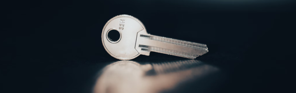 Een close-up van een metalen sleutel met geëtste cijfers, gebruikt voor wachtwoordbeveiliging, liggend op een reflecterend donker oppervlak met een onscherpe achtergrond.