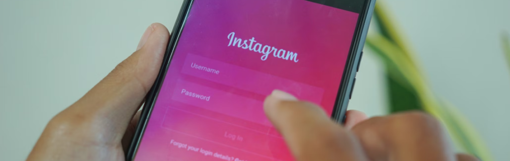 Een persoon houdt een smartphone vast waarop het inlogscherm van Instagram wordt weergegeven, met velden voor een gebruikersnaam en wachtwoord, zich niet bewust van mogelijke clickjacking-bedreigingen die op de loer liggen achter onschuldig ogende knoppen.