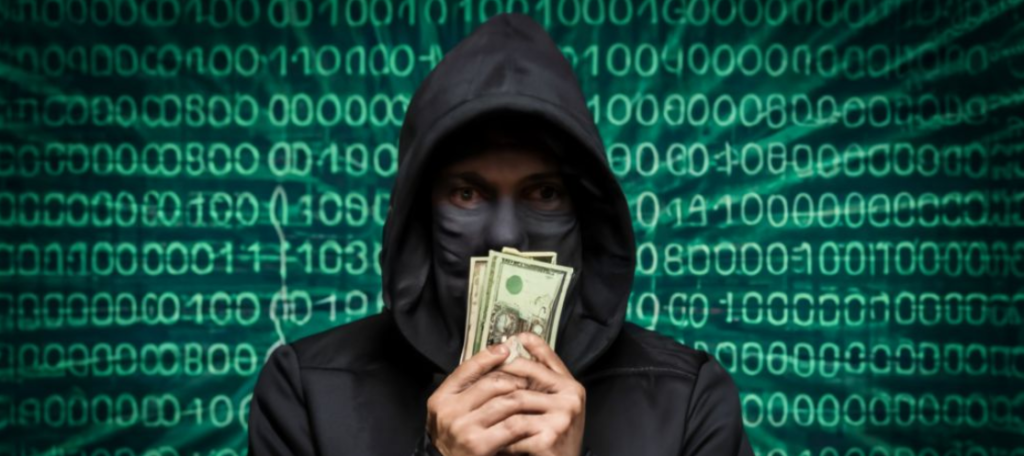 Een persoon die een hoodie en een masker draagt, houdt verschillende Amerikaanse dollarbiljetten vast voor een achtergrond met binaire code, wat duidt op een verband met bedrijven die het doelwit zijn van een hack voor losgeld.