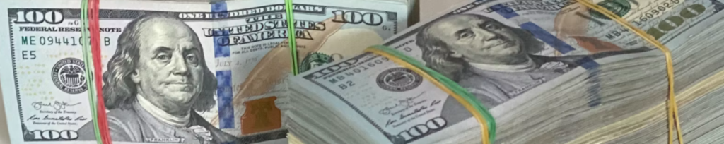 Stapels Amerikaanse honderd-dollarbiljetten, gebonden met gekleurde elastiekjes, die doen denken aan ransomware-betalingen of cruciale back-ups voor onvoorziene omstandigheden.