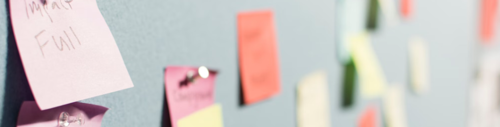 Close-up van een prikbord met verschillende gekleurde plakbriefjes en papieren bevestigd met punaises, waarin onderwerpen als digitale fraude worden besproken. Er is iets geschreven op de plakbriefjes, wat hun grote impact benadrukt.