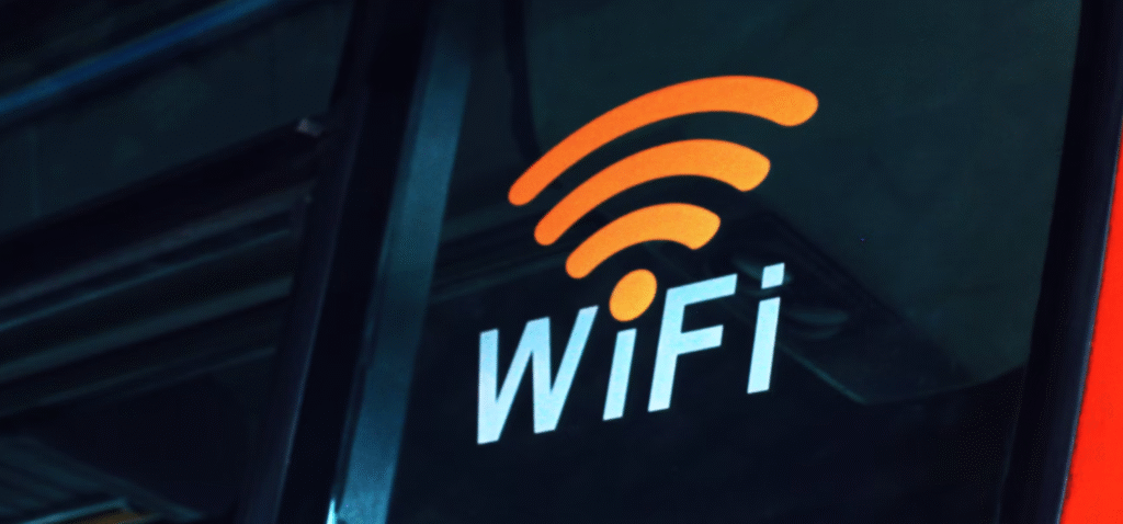 Een close up van een oranje wifi symbool boven het woord "wifi" op een glazen oppervlak, wat waarschijnlijk duidt op de beschikbaarheid van draadloos internet. dit benadrukt het belang van wifi veiligheid, vooral op openbare wifi netwerken.